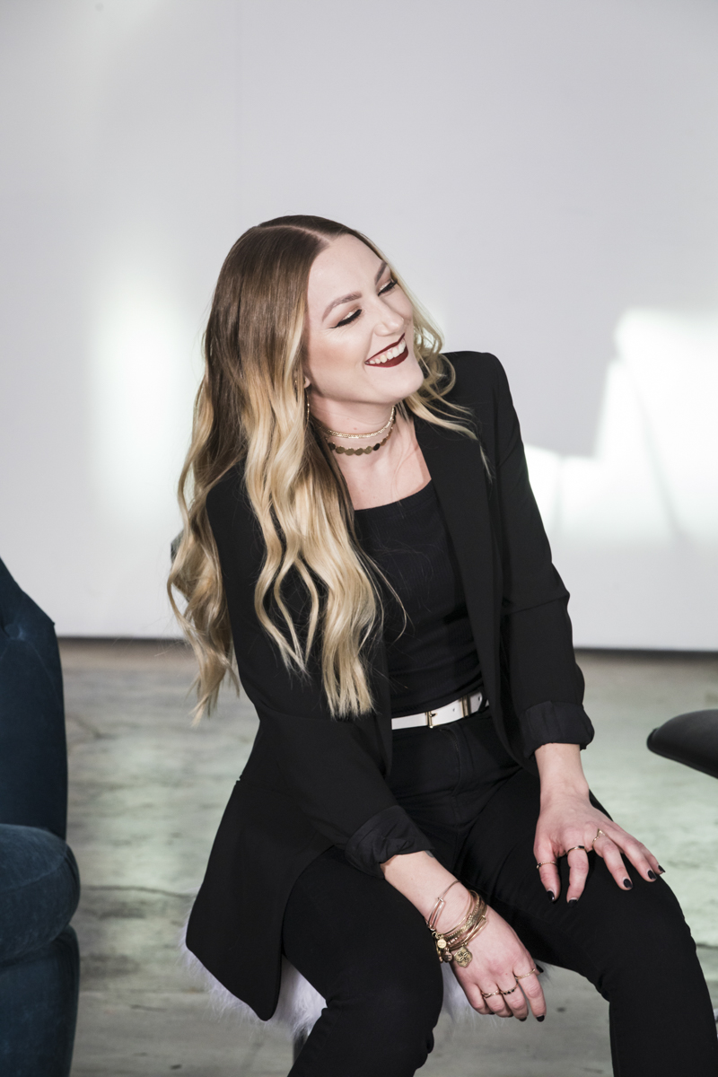 Woman smiling leaning to one side with hand on knee.